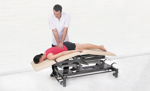 A person lying on the massage table, and a physiotherapist performing spinal massage.