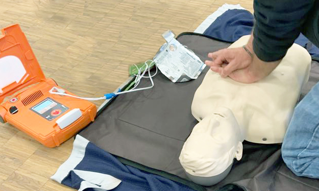 A man performs CPR on a dummy to explain the procedure to participants.